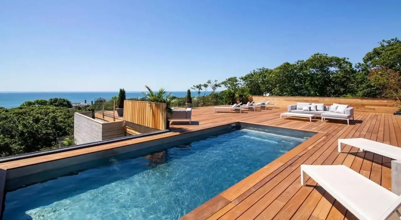 Terrasse en bois autour d'une piscine, vue sur la mer