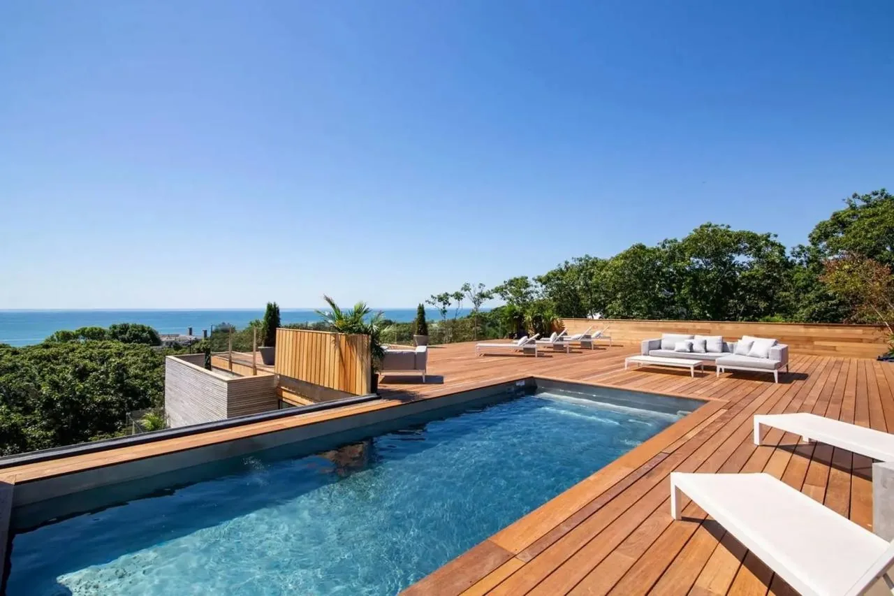 Terrasse en bois autour d'une piscine, vue sur la mer