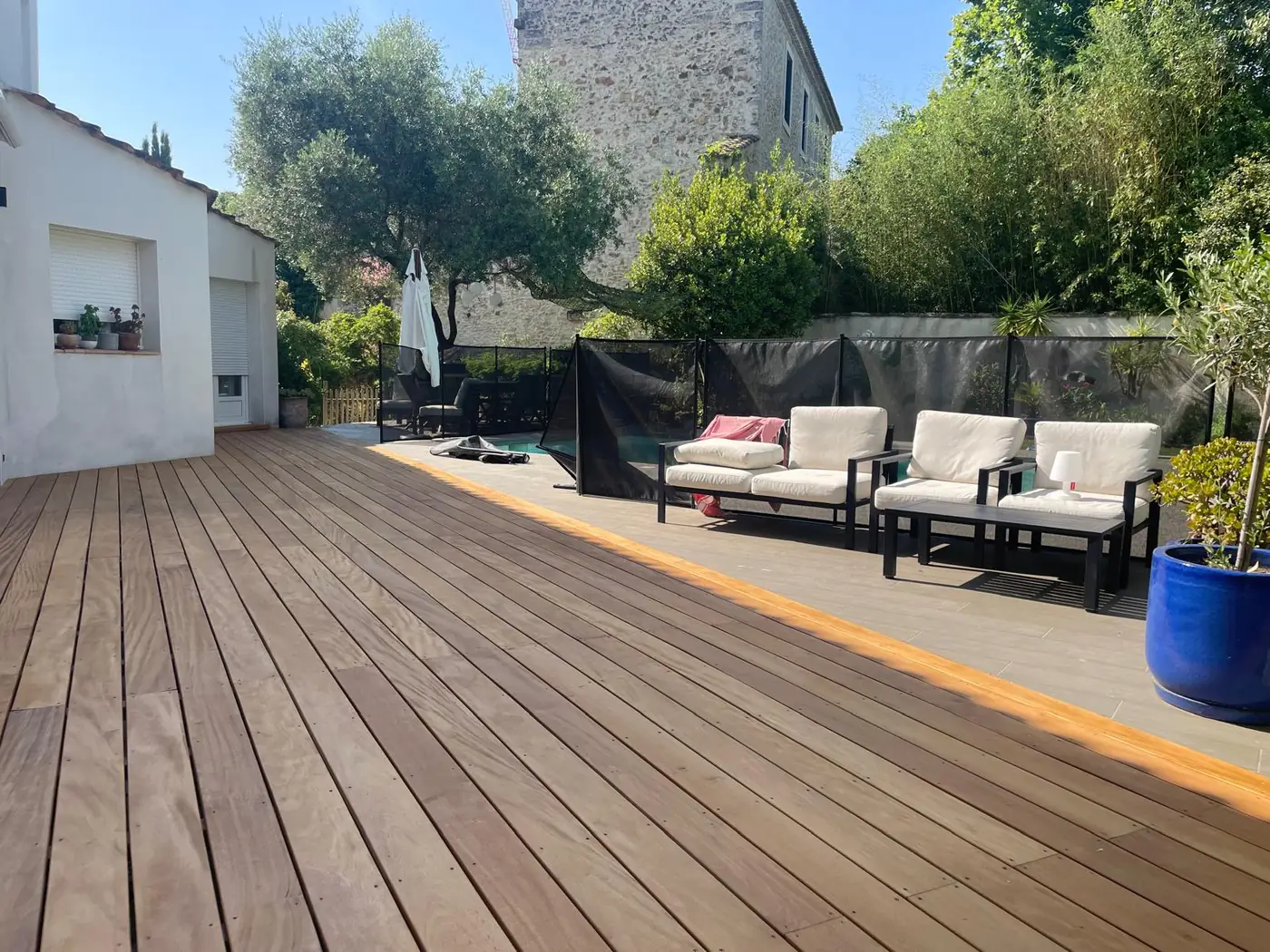 Grande terrasse en bois devant une maison et un salon de jardin