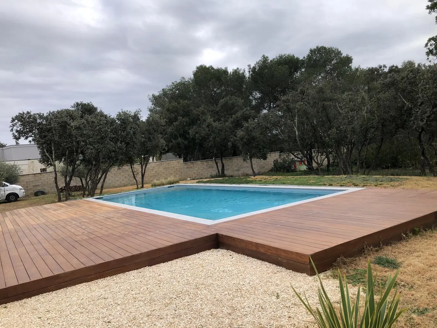 Plage de piscine en bois dans un jardin arboré