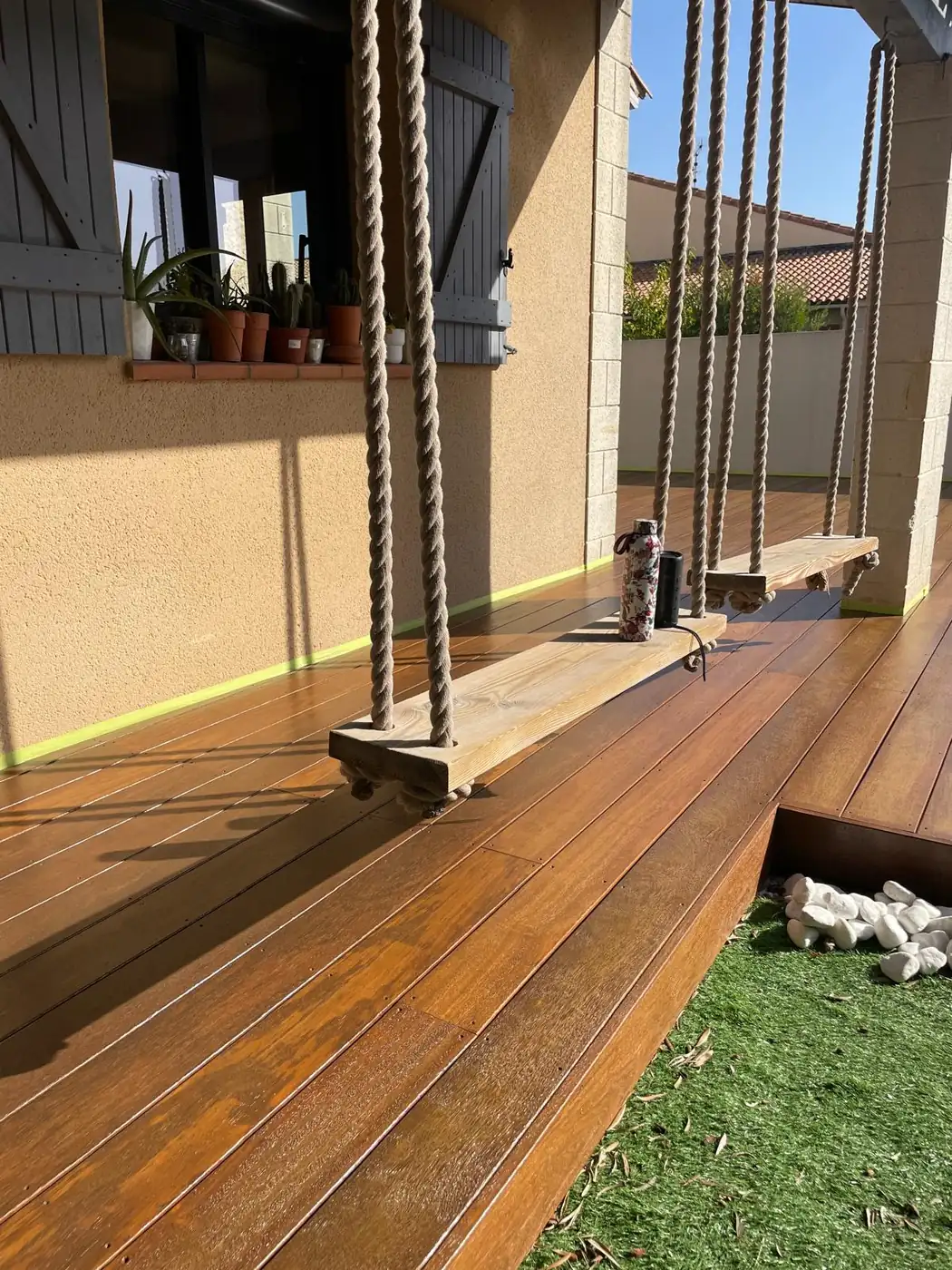Terrasse en bois protégée, sous une balançoire suspendue